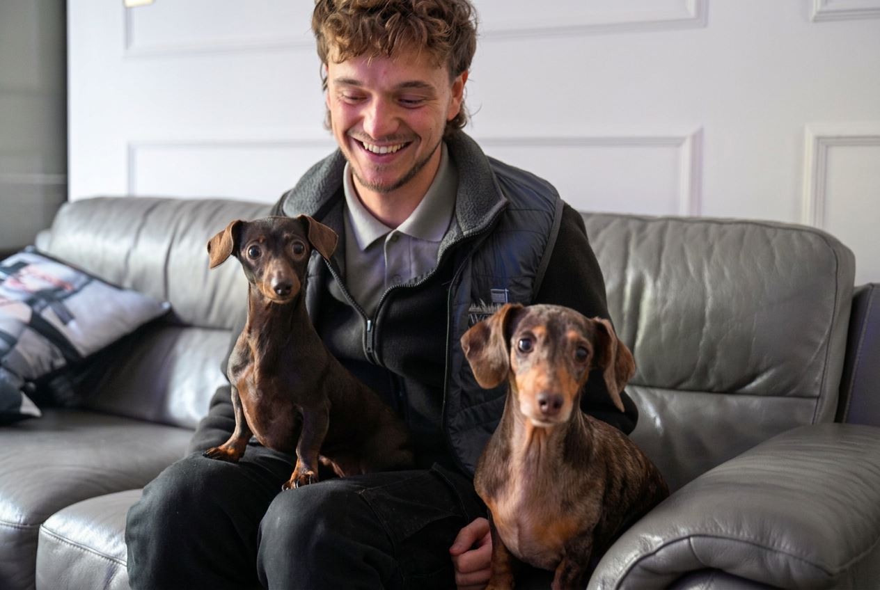 Adam sitting on the living room sofa with Daphne and Dolly, our Miniature Dachshunds
